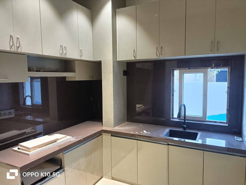 Modular kitchen with ivory shutters, dark granite counter, tall units and a window over the sink