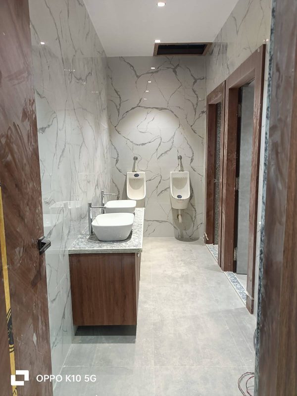 Washroom clad in white marble with twin counter basins and a wooden vanity